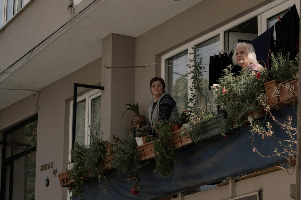Two senior women enjoying a balcony view surrounded by potted plants in Istanbul.