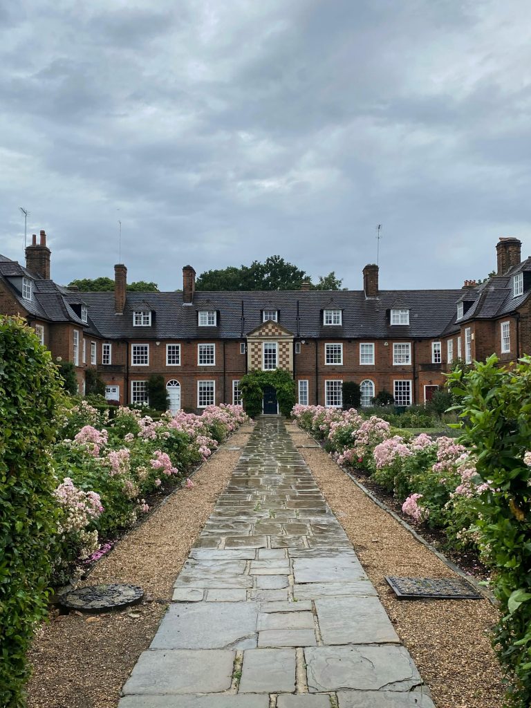 Explore a beautiful stone path lined with lush pink flowers in Hampstead Garden Suburb, London.